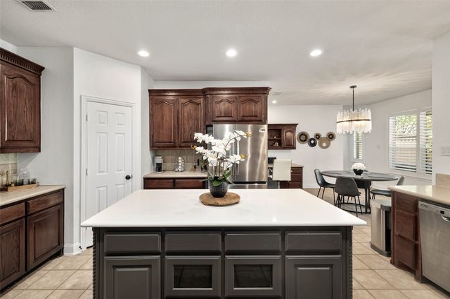Kitchen featuring light tile patterned floors, light countertops, backsplash, and appliances with stainless steel finishes | Image 12