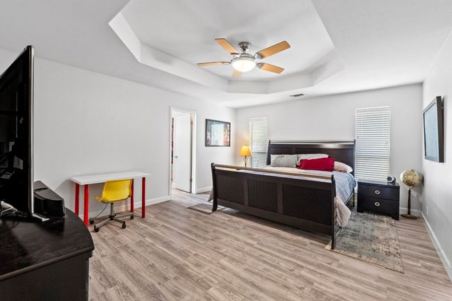 Bedroom with a tray ceiling, wood finished floors, baseboards, and ceiling fan | Image 15