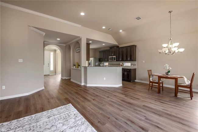 Kitchen featuring stainless steel appliances, a chandelier, arched walkways, light wood-style flooring, and light countertops | Image 6