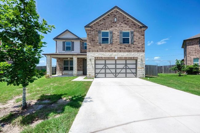 View of front of home with stone siding, driveway, a garage, and covered porch | Image 5