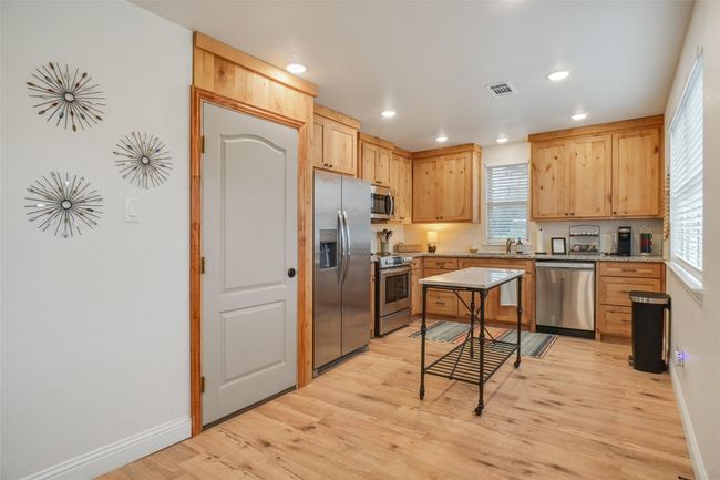 Kitchen featuring light stone counters, sink, stainless steel appliances, and a healthy amount of sunlight | Image 8