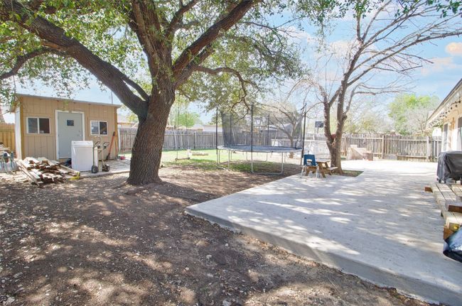 View of yard featuring a fenced backyard, a patio, an outdoor structure, and a trampoline | Image 17
