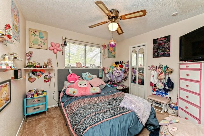 Bedroom with a closet, carpet flooring, a textured ceiling, baseboards, and a ceiling fan | Image 17