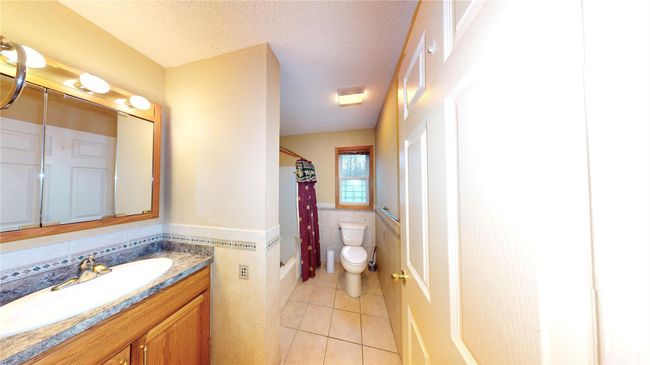 Full bath with tile walls, a wainscoted wall, toilet, tile patterned floors, and a textured ceiling | Image 21