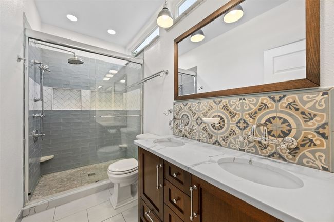 Bathroom featuring double vanity, a shower stall, tile patterned floors, decorative backsplash, and recessed lighting | Image 18