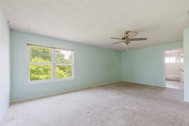 Carpeted empty room featuring ceiling fan, a textured ceiling, and baseboards | Image 14