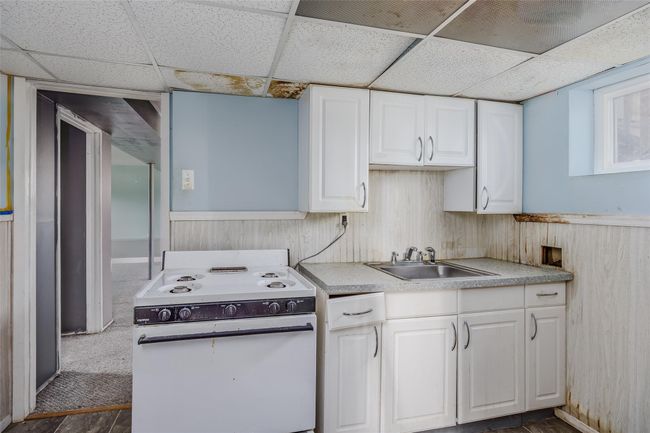 Kitchen featuring a sink, white cabinets, white range with electric cooktop, and wainscoting | Image 26