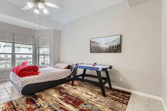 Bedroom with vaulted ceiling, light tile patterned flooring, and a ceiling fan | Image 14