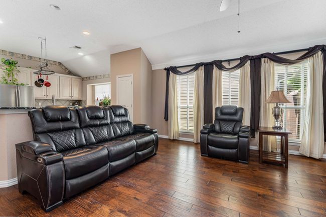 Living area featuring lofted ceiling, hardwood floors, a ceiling fan, crown molding, baseboards, and recessed lighting | Image 18