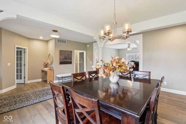 dining space featuring ceiling fan with notable chandelier, visible vents, baseboards, and hardwood / wood-style flooring | Image 9
