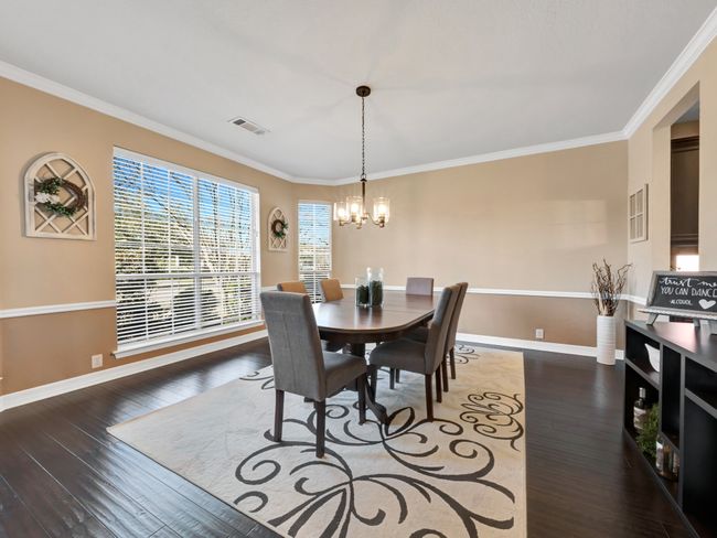 Dining space featuring a chandelier, hardwood / wood-style floors, visible vents, and crown molding | Image 8
