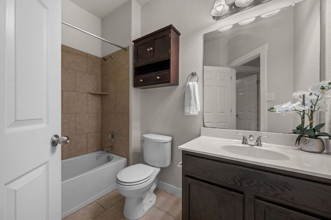 Full bath featuring vanity, toilet, bathing tub / shower combination, tile patterned flooring, and baseboards | Image 23