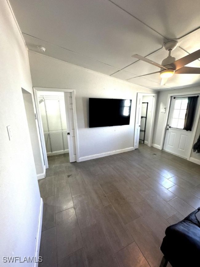 Unfurnished living room featuring lofted ceiling, a ceiling fan, dark wood-style flooring, and baseboards | Image 11
