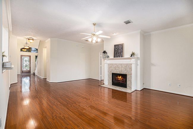 Living room facing entry with gas log fireplace and ceiling fan. | Image 9