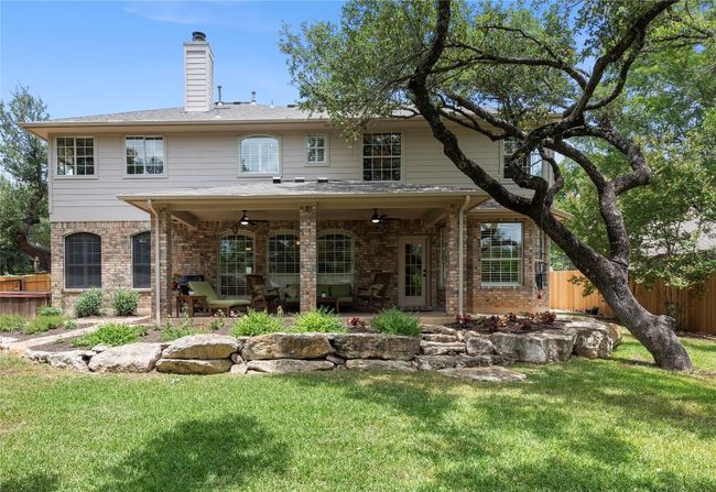 Covered patio with ceiling fans and stone accents, overlooking a spacious backyard | Image 31