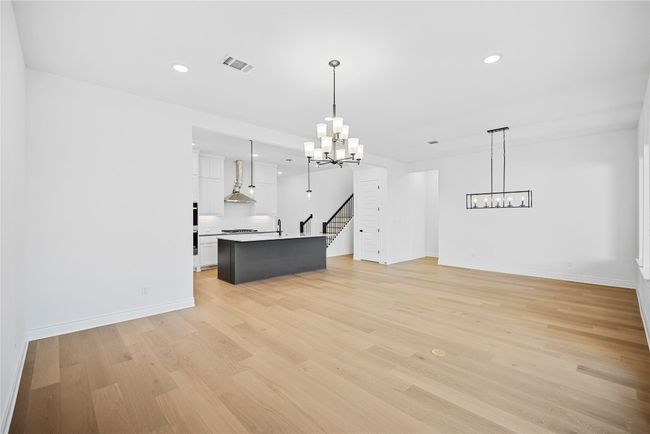 Unfurnished living room featuring a chandelier, recessed lighting, light wood-style flooring, and stairs | Image 17