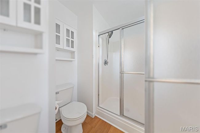 Full bathroom with toilet, a stall shower, wood finished floors, and baseboards | Image 17
