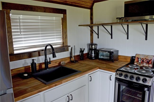 Kitchen with butcher block countertops, appliances with stainless steel finishes, a sink, and white cabinetry | Image 20