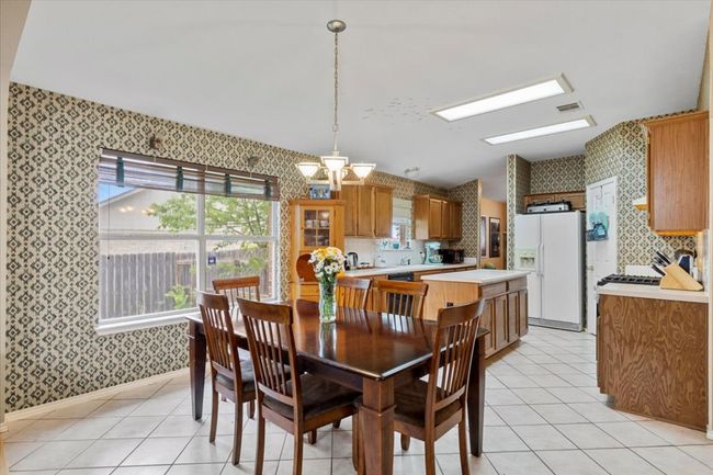 Dining room featuring wallpapered walls, light tile patterned floors, a chandelier, and baseboards | Image 13