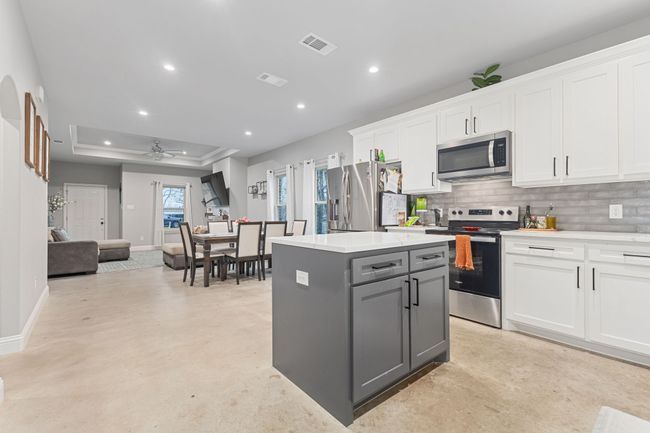 Kitchen featuring a tray ceiling, stainless steel appliances, and white cabinets | Image 14