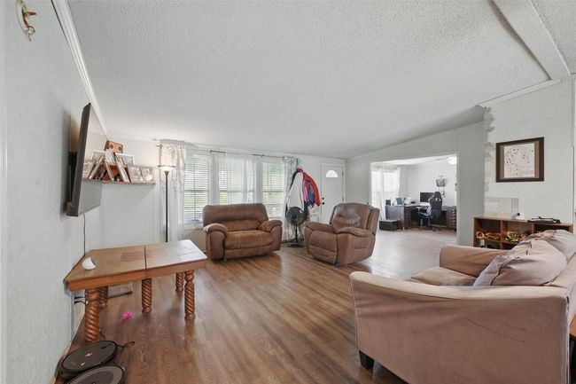 Living room featuring a textured ceiling, an office area, wood finished floors, and vaulted ceiling | Image 4