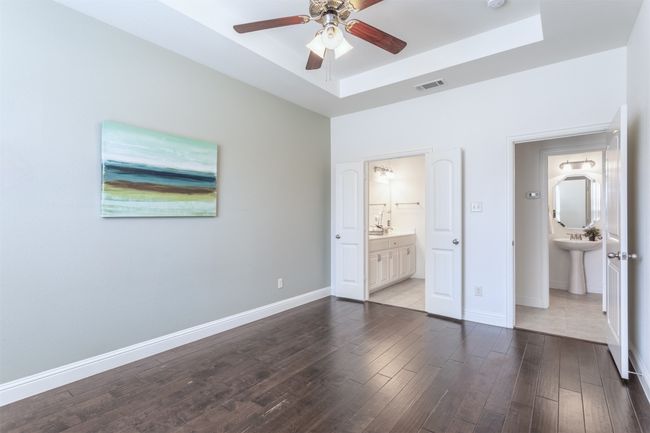 Unfurnished bedroom with visible vents, dark wood-type flooring, ensuite bath, baseboards, and a raised ceiling | Image 17