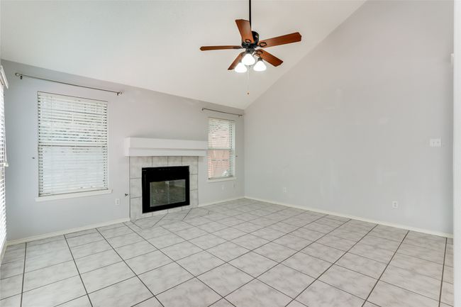 Unfurnished living room featuring high vaulted ceiling, baseboards, a ceiling fan, and a tile fireplace | Image 9