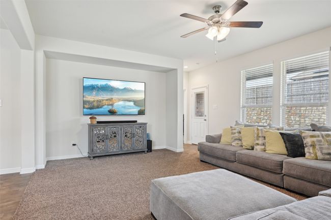 Carpeted living area featuring ceiling fan and baseboards | Image 6