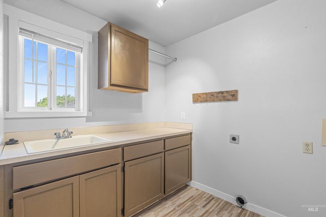 Laundry room featuring hookup for an electric dryer, light wood-style flooring, and cabinet space | Image 24
