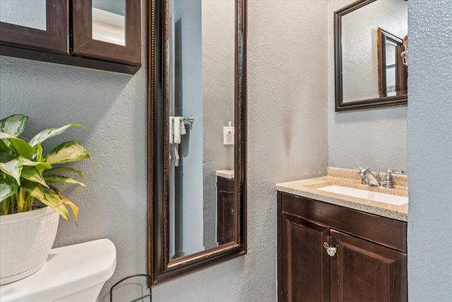 Bathroom featuring a textured wall, toilet, and vanity | Image 11