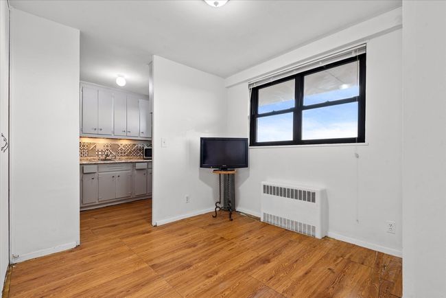 Unfurnished living room with light wood-style flooring, baseboards, and radiator | Image 6