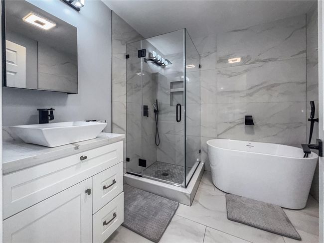 Bathroom featuring marble look tiles, vanity, a freestanding tub, and a stall shower | Image 23
