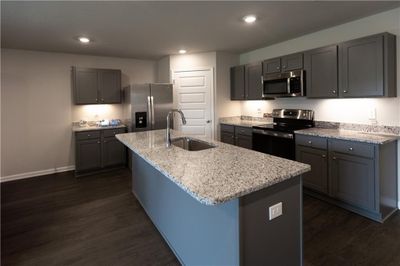 Kitchen with a center island with sink, appliances with stainless steel finishes, dark wood-type flooring, and light stone countertops | Image 3