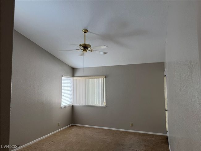Carpeted empty room featuring ceiling fan and vaulted ceiling | Image 8