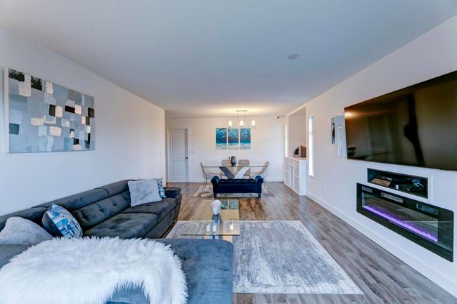 Living area featuring wood finished floors, baseboards, and a notable chandelier | Image 7