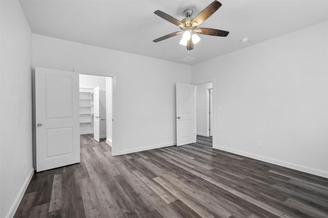 Unfurnished bedroom featuring dark wood-type flooring, a spacious closet, ceiling fan, and a closet | Image 9