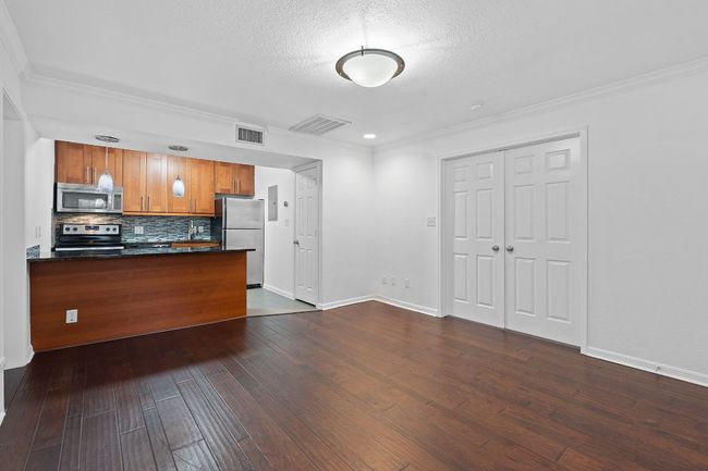 Kitchen with dark wood-style floors, visible vents, appliances with stainless steel finishes, and brown cabinetry | Image 13