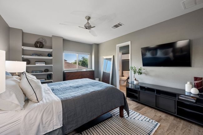 Bedroom featuring visible vents, light wood-type flooring, connected bathroom, and a ceiling fan | Image 16