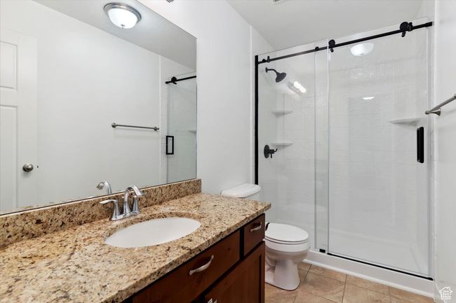 Full bathroom with a stall shower, vanity, toilet, and tile patterned floors | Image 26