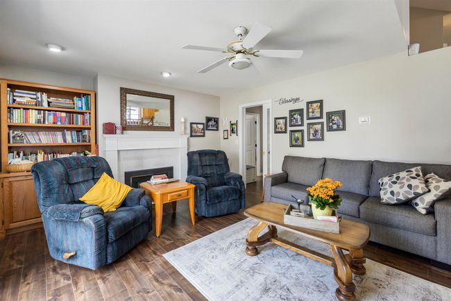 Living area with wood finished floors, a tiled fireplace, and ceiling fan | Image 12