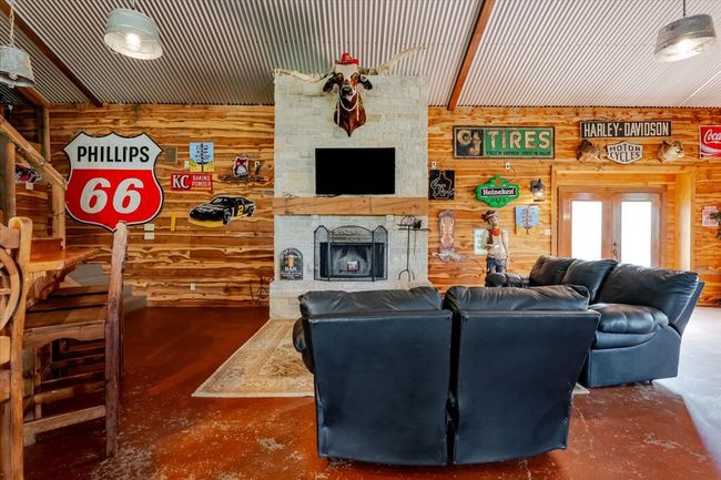 Living area with wooden walls, a stone fireplace, and concrete floors | Image 31