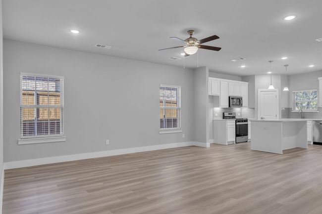 Unfurnished living room featuring baseboards, visible vents, light wood-type flooring, and a ceiling fan | Image 6