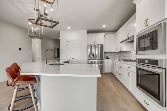 Kitchen with appliances with stainless steel finishes, light wood-style flooring, tasteful backsplash, under cabinet range hood, and recessed lighting | Image 7