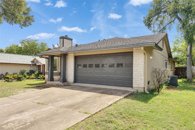 View of front of house featuring a front yard, concrete driveway, a chimney, a garage, and stone siding | Image 23