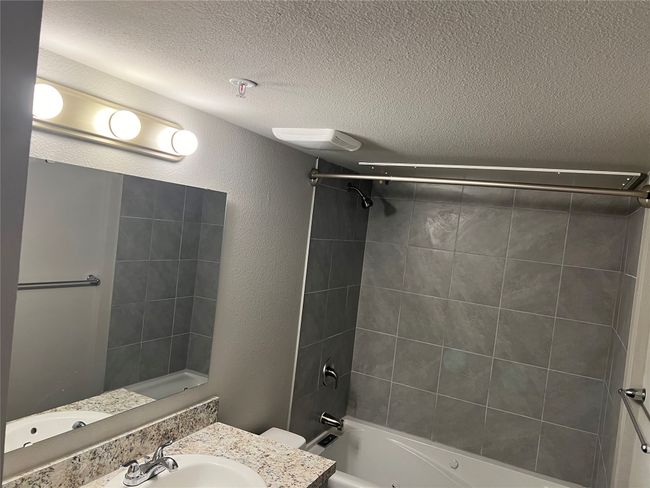 Bathroom featuring a textured ceiling, shower / tub combination, vanity, toilet, and a textured wall | Image 11