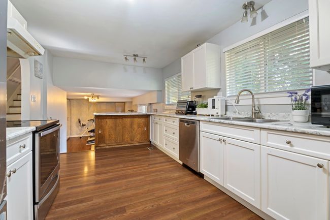 Kitchen featuring stainless steel appliances, dark wood-style floors, white cabinetry, and a sink | Image 12