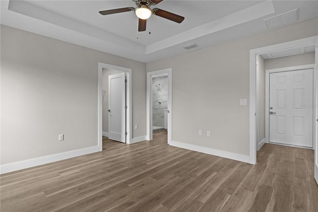 Primary walk-in closet on the left and ensuite bathroom in the middle. Through the open bedroom door is the door to the garage. | Image 22