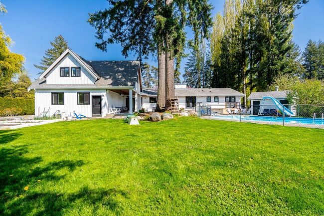 Back of property featuring fence, board and batten siding, a fenced in pool, and a lawn | Image 27