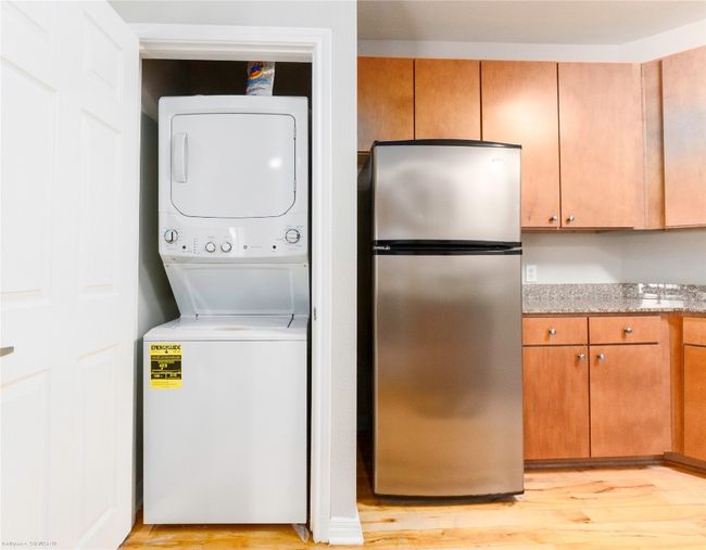 Laundry room featuring stacked washer / dryer and light wood finished floors | Image 20