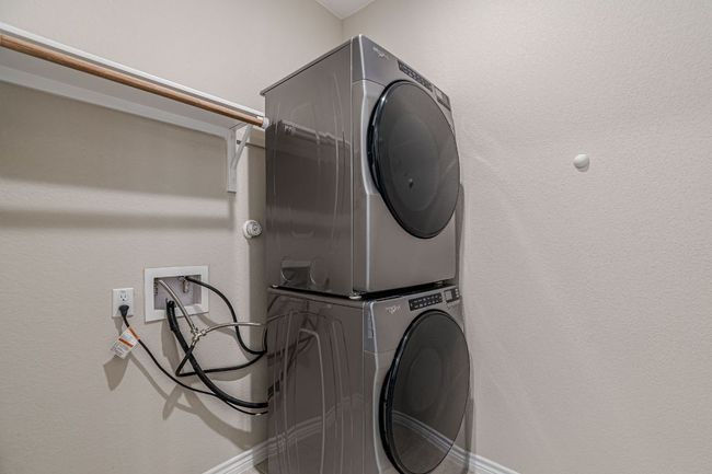 Washroom featuring stacked washing machine and dryer and a textured wall | Image 22